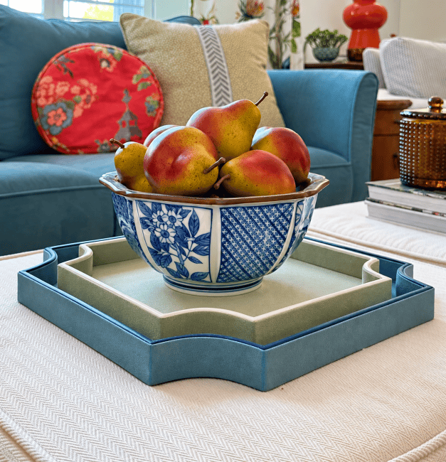 Elegant blue and white ceramic bowl filled with apples on a coffee table.