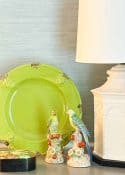 Colorful bird figurines with red berries, lime green plate, cream lamp, and decorative box.